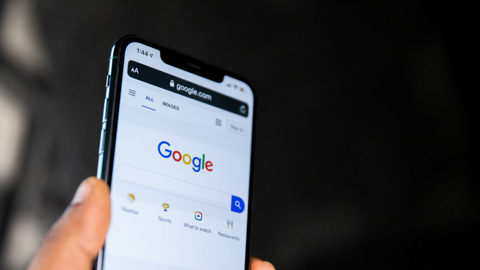 Ruka drží mobil s otevřeným vyhledáváním Google
