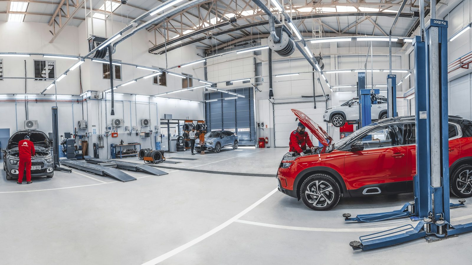 Světlá dílna autoservisu, mechanik u auta na zvedáku